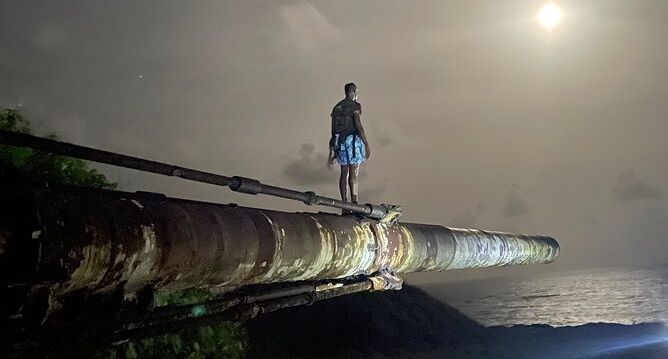 Hike guide standing on the HARP Gun in Barbados under a moonlit sky