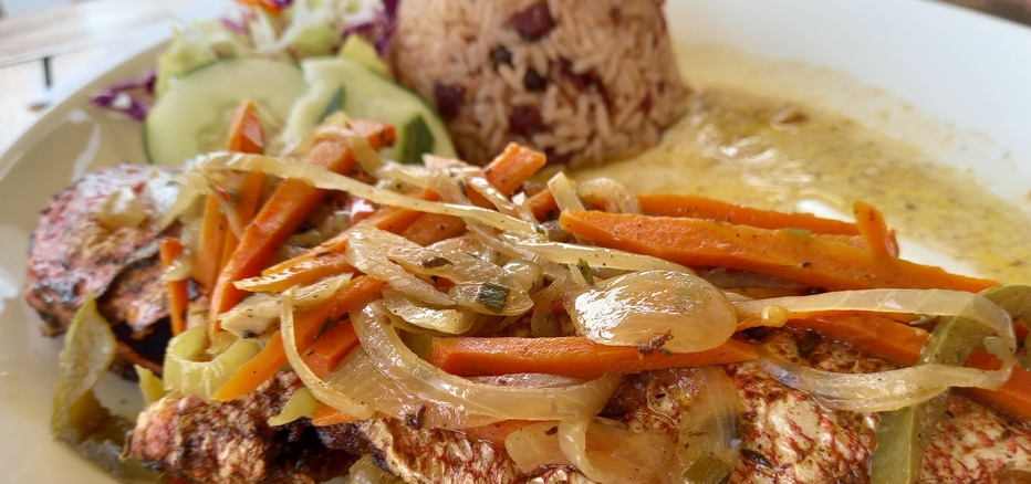 Steamed fish served with veggies and rice & peas.