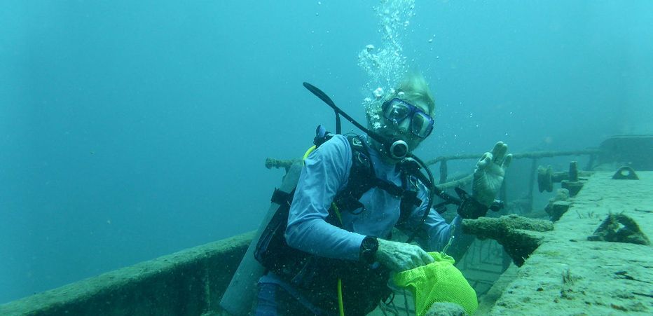 Scuba diver over a wreck off Barbados waving to camera.