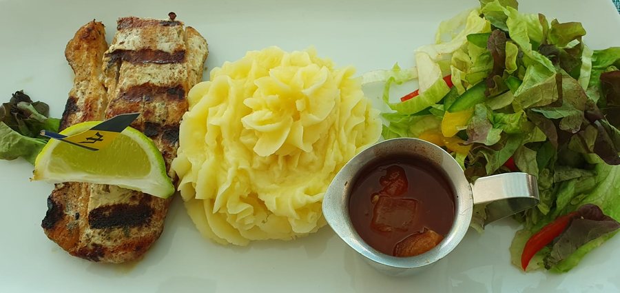 Grilled fish with mashed potatoes, salad, and gravy.