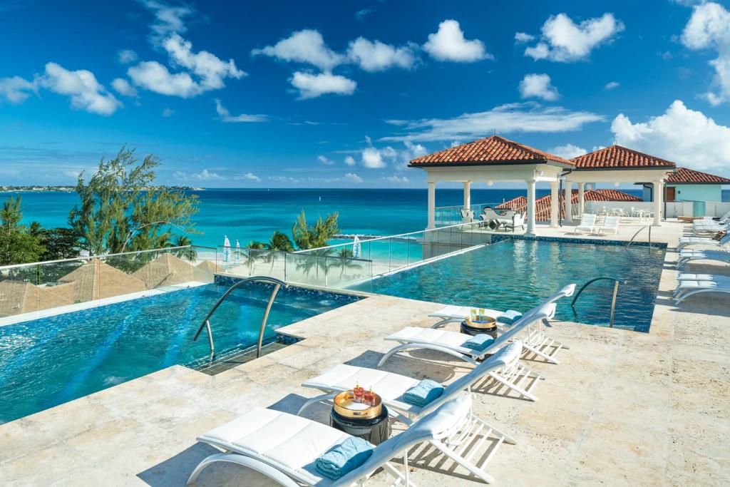 Rooftop pool with loungers overlooking the turquoise seas at Sandals Royal Barbados.