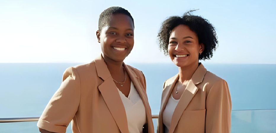 Two smiling ladies against an ocean backdrop
