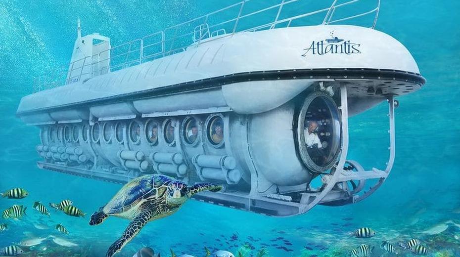 Atlantis submarine surrounded by fish, corals and a sea turtle.
