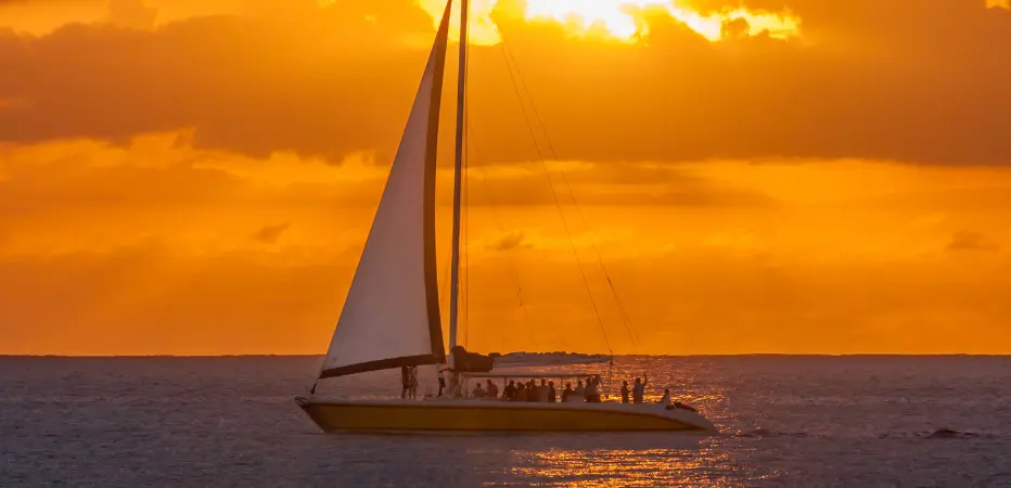 A catamaran sails along Barbados' west coast as the sun sets with a brilliant orange display!