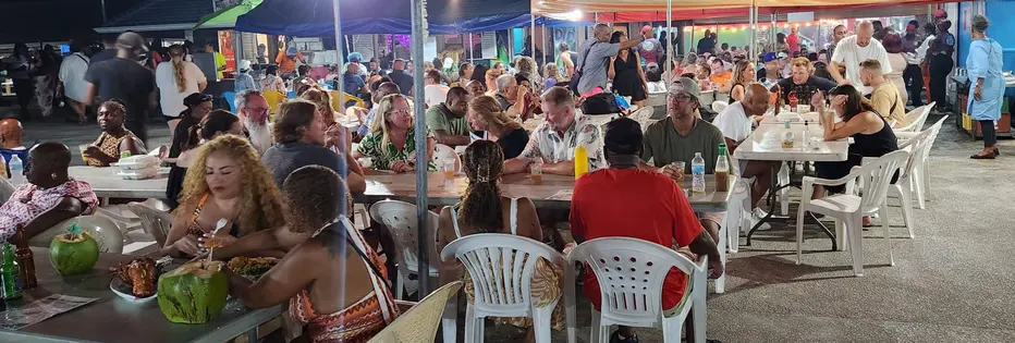 A crowd of locals and visitors eating and drinking at Oistins Fish Fry