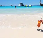 Cocktail on the sand with turquoise waters in the background
