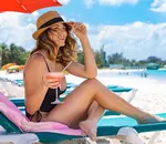 Woman smiling with drink in hand on a lounger at Carlisle Bay