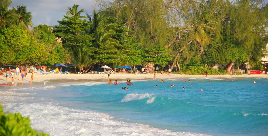 Beachgoers frolicking in warm turquoise waters at Rockley/Accra Beach