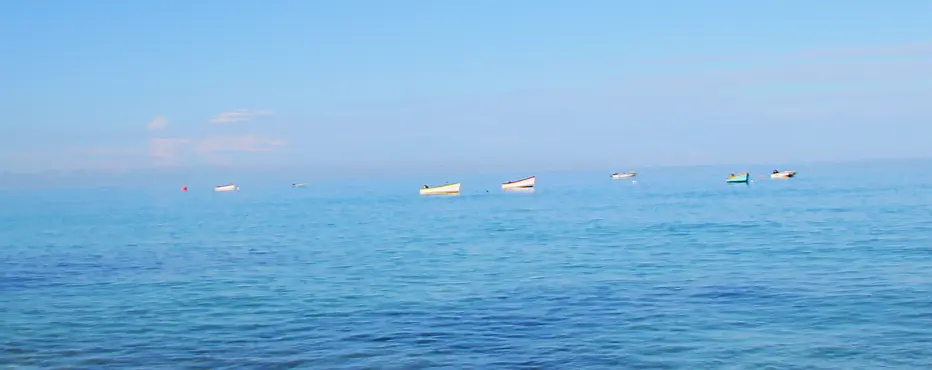Small fishing boats bob on tranquil waters