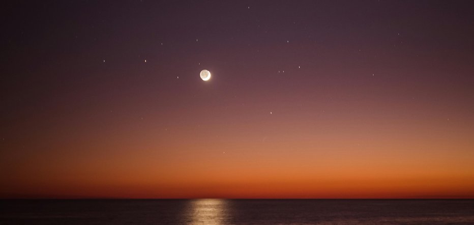 View of the night sky with full mooon and stars, taken from the beach