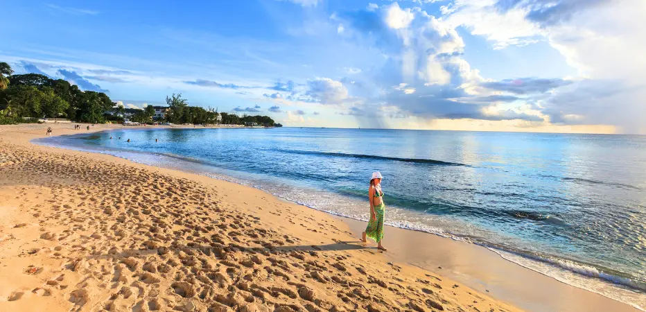 Lady strolls along the waters edge as the beach stretches behind her