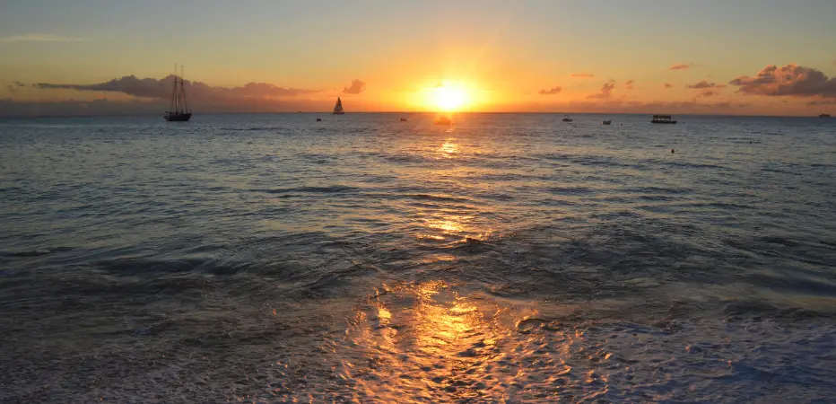 Sunset reflects off ocean waters, spreading shades of gold and orange