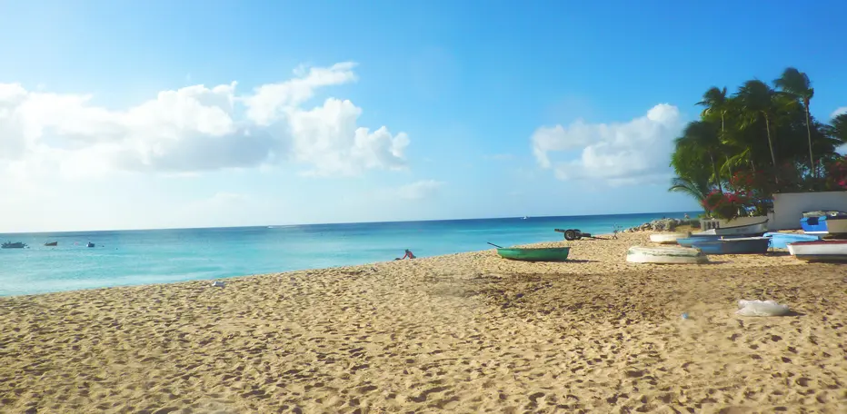 View across soft sands to the calms turquoise sea, with small fishing boats on the sand