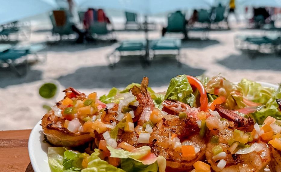 Grilled shrimp on salad, with beach in the background