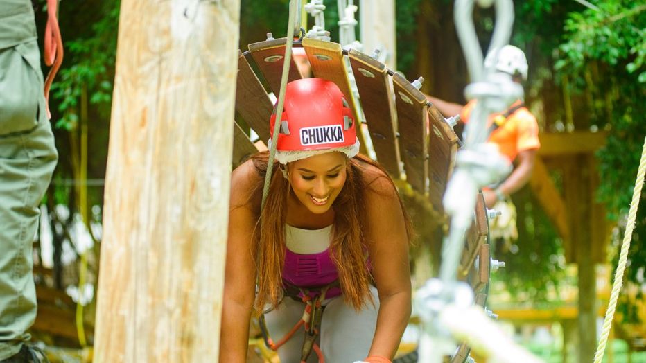 Smiling lady climbing through the wobbly wooden tunnel